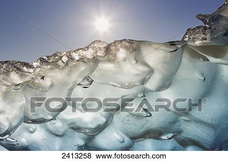 Stock Photo - Close up of ice surface of iceberg broken off Mendenhall Glacier floating in Mendenhall lake, flipping over and exposing blue polished ice from being underwater; Juneau, Alaska, United States of America. Fotosearch