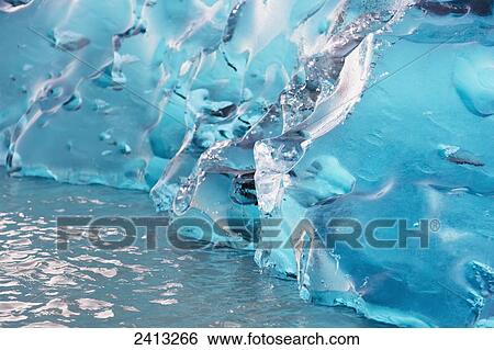 Stock Photograph - Close up of ice surface of iceberg broken off Mendenhall Glacier floating in Mendenhall lake, flipping over and exposing blue polished ice from being underwater; Juneau, Alaska, United States of America. Fotosearch