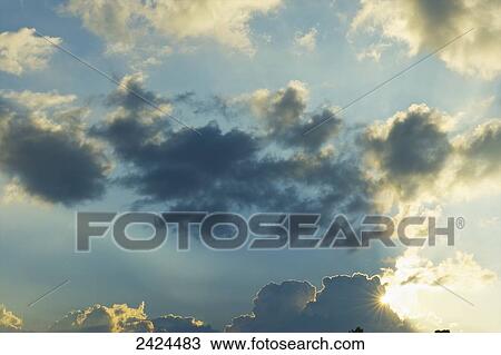 Stock Image - Clouds in the blue sky illuminated by sunlight; Ulpotha, Embogama, Sri Lanka. Fotosearch