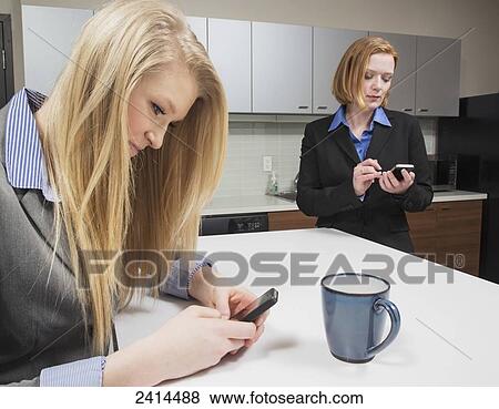 Co-workers texting during a coffee break; Edmonton, Alberta, Canada View Large Photo Image Stock Photo - Co-workers texting during a coffee break; Edmonton, Alberta, Canada. Fotosearch