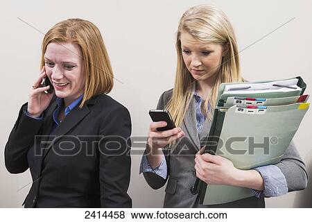 Picture - Co-workers wasting time talking and texting; Edmonton, Alberta, Canada. Fotosearch - Search Stock Photos, Images, Print Photographs, and Photo Clip Art