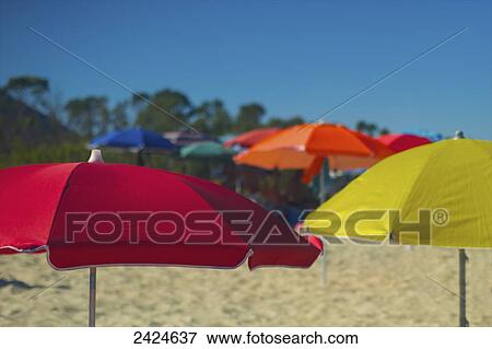 Stock Photo - Colourful umbrellas on the beach with a blue sky; Sardinia, Italy. Fotosearch