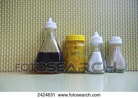 Stock Image - Condiments lined up on a restaurant table; London, England. Fotosearch