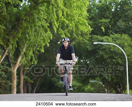 Cyclist riding an electric bike; Edmonton, Alberta, Canada View Large Photo Image Picture - Cyclist riding an electric bike; Edmonton, Alberta, Canada. Fotosearch