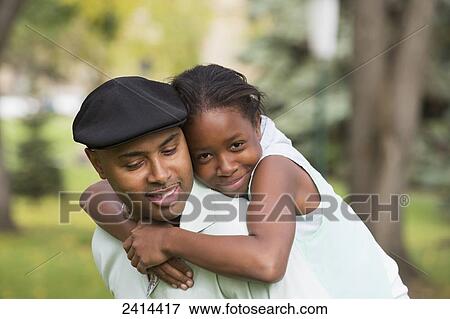 Stock Photo - Daughter hugging her father in a park; Edmonton, Alberta, Canada. Fotosearch
