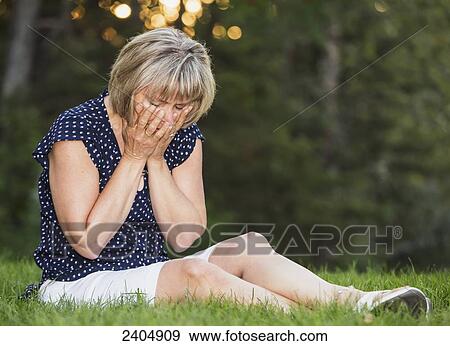 Stock Photo - Distraught woman praying in a park; Edmonton, Alberta, Canada. Fotosearch
