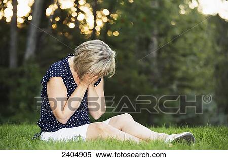 Stock Photography - Distraught woman praying in a park; Edmonton, Alberta, Canada. Fotosearch