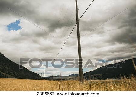 Stock Image - Electrical transmission lines through the valley and a cloudy sky; Peachland, British Columbia, Canada. Fotosearch
