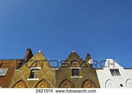 Facade of residential buildings with peaked rooflines and a blue sky, Camden; London, England View Large Photo Image Picture - Facade of residential buildings with peaked rooflines and a blue sky, Camden; London, England. Fotosearch