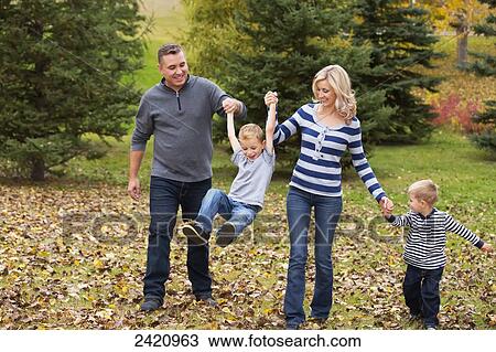 Family walking and holding hands in a park in autumn; Edmonton, Alberta, Canada View Large Photo Image Stock Image - Family walking and holding hands in a park in autumn; Edmonton, Alberta, Canada. Fotosearch