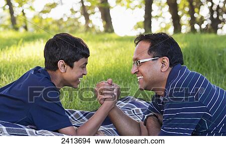 Father and son arm wrestling in a park; Edmonton, Alberta, Canada View Large Photo Image Picture - Father and son arm wrestling in a park; Edmonton, Alberta, Canada. Fotosearch