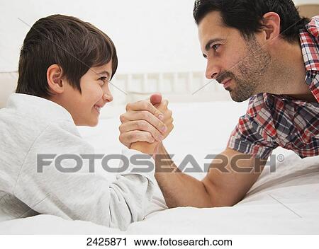 Father and son arm wrestling together on a bed; Langley, British Columbia, Canada View Large Photo Image Stock Image - Father and son arm wrestling together on a bed; Langley, British Columbia, Canada. Fotosearch