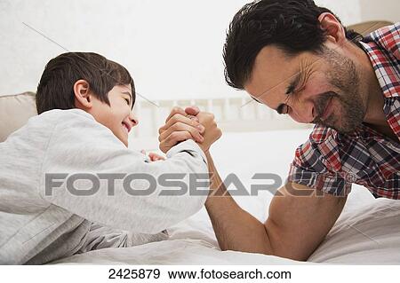 Father and son arm wrestling together on a bed; Langley, British Columbia, Canada View Large Photo Image Stock Photo - Father and son arm wrestling together on a bed; Langley, British Columbia, Canada. Fotosearch