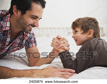 Father and son arm wrestling together on a bed; Langley, British Columbia, Canada View Large Photo Image Stock Photography - Father and son arm wrestling together on a bed; Langley, British Columbia, Canada. Fotosearch