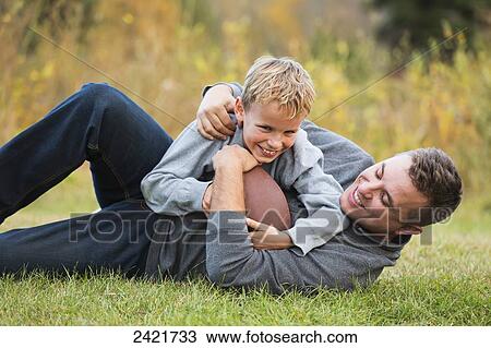Father and son playing football in a park in autumn; Edmonton, Alberta, Canada View Large Photo Image Stock Image - Father and son playing football in a park in autumn; Edmonton, Alberta, Canada. Fotosearch