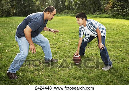 Father and son playing football in a park; Edmonton, Alberta, Canada View Large Photo Image Stock Photo - Father and son playing football in a park; Edmonton, Alberta, Canada. Fotosearch