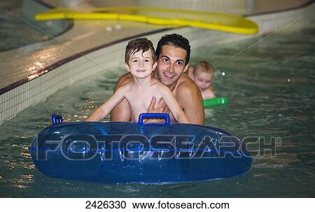 Father and son playing in a swimming pool on an inflatable tube; Edmonton, Alberta, Canada View Large Photo Image Stock Image - Father and son playing in a swimming pool on an inflatable tube; Edmonton, Alberta, Canada. Fotosearch