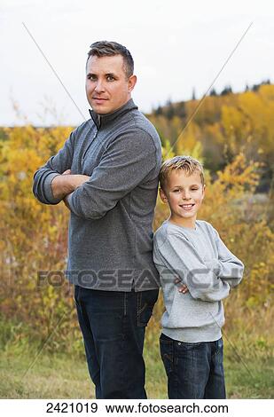 Father and son posing outdoors in a park in autumn; Edmonton, Alberta, Canada View Large Photo Image Stock Photo - Father and son posing outdoors in a park in autumn; Edmonton, Alberta, Canada. Fotosearch