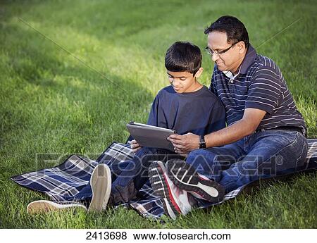 Father and son spending quality time together outdoors looking at a tablet; Edmonton, Alberta, Canada View Large Photo Image Stock Photo - Father and son spending quality time together outdoors looking at a tablet; Edmonton, Alberta, Canada. Fotosearch