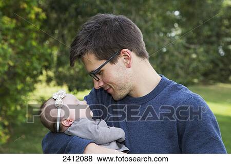Father holding his sleeping infant daughter in a park; Edmonton, Alberta, Canada View Large Photo Image Stock Photo - Father holding his sleeping infant daughter in a park; Edmonton, Alberta, Canada. Fotosearch