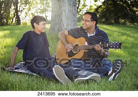 Father playing the guitar for his son in a park; Edmonton, Alberta, Canada View Large Photo Image Stock Photography - Father playing the guitar for his son in a park; Edmonton, Alberta, Canada. Fotosearch