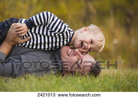 Father playing with his young son on the grass in a park in autumn; Edmonton, Alberta, Canada View Large Photo Image Stock Image - Father playing with his young son on the grass in a park in autumn; Edmonton, Alberta, Canada. Fotosearch