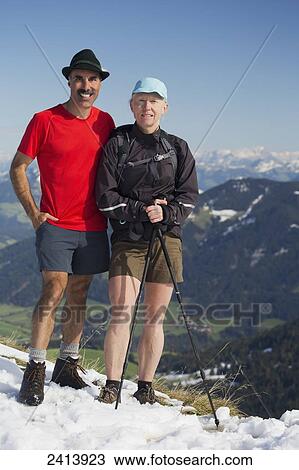 Female and male hiker on top of snow covered mountain with valley below and mountain ranges in the distance with blue sky; Alpbach, Austria View Large Photo Image Stock Image - Female and male hiker on top of snow covered mountain with valley below and mountain ranges in the distance with blue sky; Alpbach, Austria. Fotosearch