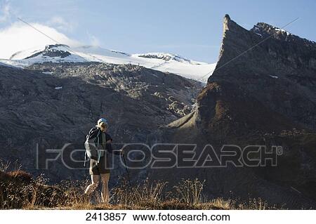 Female hiker along a trail with rugged mountains and glacier in the background; Austria View Large Photo Image Stock Photo - Female hiker along a trail with rugged mountains and glacier in the background; Austria. Fotosearch
