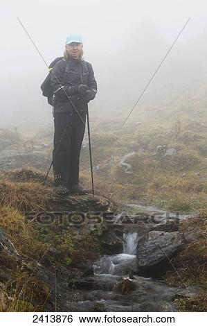 Female hiker in the fog next to a small stream wallfalls in a grassy area; Lanserbach, Austria View Large Photo Image Stock Photograph - Female hiker in the fog next to a small stream wallfalls in a grassy area; Lanserbach, Austria. Fotosearch