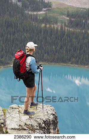 Female hiker on rock cliff overlooking blue alpine lake; British Columbia, Canada View Large Photo Image Stock Image - Female hiker on rock cliff overlooking blue alpine lake; British Columbia, Canada. Fotosearch