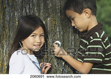 Stock Image - Five Year Old Sister And Seven Year Old Brother With Stethescope On Tree, Winnipeg, Canada. Fotosearch
