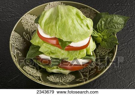 Stock Photo - Food - Caprese Tower Salad with a sliced baby Iceberg lettuce head. Ingredients include buffalo mozzarella cheese, tomatoes, basil, marjoram, thyme, oregano, olive oil and vinegar.. Fotosearch