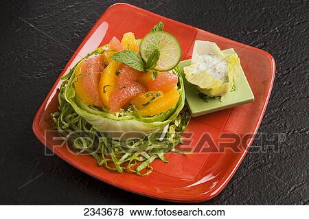 Stock Photo - Food - Citrus Mint Salad with ginger honey dressing. Ingredients include a baby Iceberg lettuce head, grapefruit and orange segments, mint, yogurt, ginger, honey and lime slice.. Fotosearch