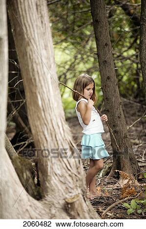 Stock Image - Girl Walking Through Woods Holding Stick, Ontario. Fotosearch