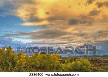 Glowing golden clouds over rugged mountains in Grand Teton National Park; Wyoming, United States of America View Large Photo Image Stock Image - Glowing golden clouds over rugged mountains in Grand Teton National Park; Wyoming, United States of America. Fotosearch