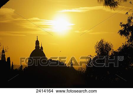 Glowing sun in a golden sky with silhouettes of dome rooftops; Barcelona, Spain View Large Photo Image Picture - Glowing sun in a golden sky with silhouettes of dome rooftops; Barcelona, Spain. Fotosearch