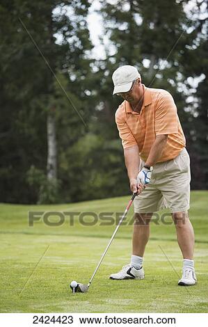 Stock Image - Golfer concentrating on hitting the ball at tee off; Edmonton, Alberta, Canada. Fotosearch