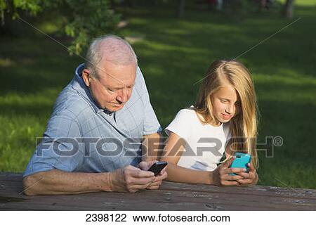 Grandfather and granddaughter checking their mobile devices together; Edmonton, Alberta, Canada View Large Photo Image Stock Image - Grandfather and granddaughter checking their mobile devices together; Edmonton, Alberta, Canada. Fotosearch