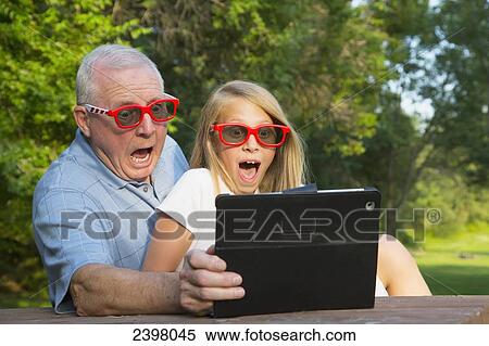 Grandfather and granddaughter watching a 3D movie on a tablet; Edmonton, Alberta, Canada View Large Photo Image Stock Photography - Grandfather and granddaughter watching a 3D movie on a tablet; Edmonton, Alberta, Canada. Fotosearch