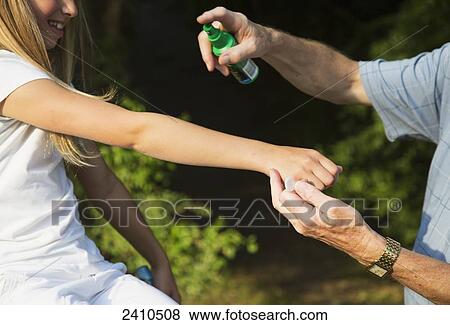 Stock Photo - Grandfather applying bug repellent to his granddaughter; St. Albert, Alberta, Canada. Fotosearch