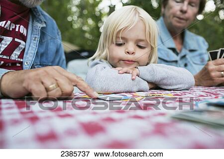 Stock Photo - Grandparents teaching a young granddaughter how to play a card game; Peachland, British Columbia, Canada. Fotosearch
