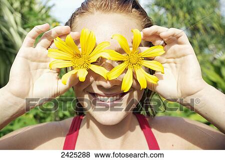 Hawaii, Kauai, A girl holds flowers in front of her eyes. View Large Photo Image Stock Photo - Hawaii, Kauai, A girl holds flowers in front of her eyes.. Fotosearch