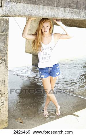 Stock Photo - Hawaii, Kauai, Hanalei Bay, A young Redheaded model poses under the pier.. Fotosearch