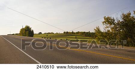 Stock Image - Highway along farmland with hay bales, near Edmonton; Alberta, Canada. Fotosearch