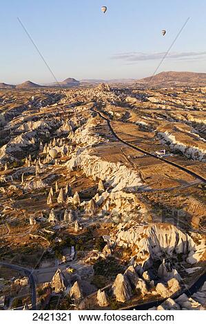 Stock Image - Hot air balloons in flight over a rugged landscape; Cappadocia, Turkey. Fotosearch