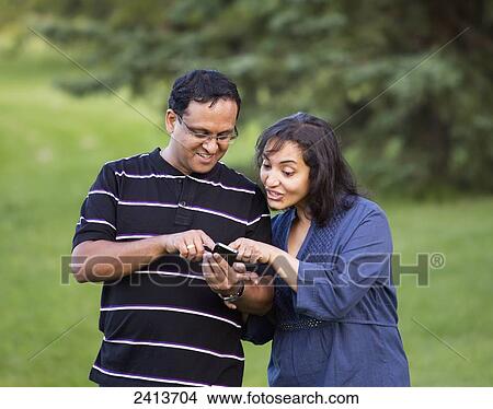 Husband and wife using social media on a smart phone; Edmonton, Alberta, Canada View Large Photo Image Picture - Husband and wife using social media on a smart phone; Edmonton, Alberta, Canada. Fotosearch
