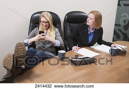 Stock Image - Intern receiving text messages during work hours; Edmonton, Alberta, Canada. Fotosearch