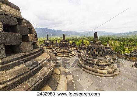 Stock Image - Latticed stone stupas containing Buddha statues on the upper terrace, Borobudur Temple Compounds, Central Java, Indonesia. Fotosearch