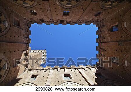 Stock Photo - Low angle view up the walls of a building to a blue sky; Siena, Italy. Fotosearch