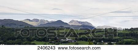 Lush green rolling hills with trees and mountains in the distance; Lake District, Cumbria, England View Large Photo Image Stock Image - Lush green rolling hills with trees and mountains in the distance; Lake District, Cumbria, England. Fotosearch